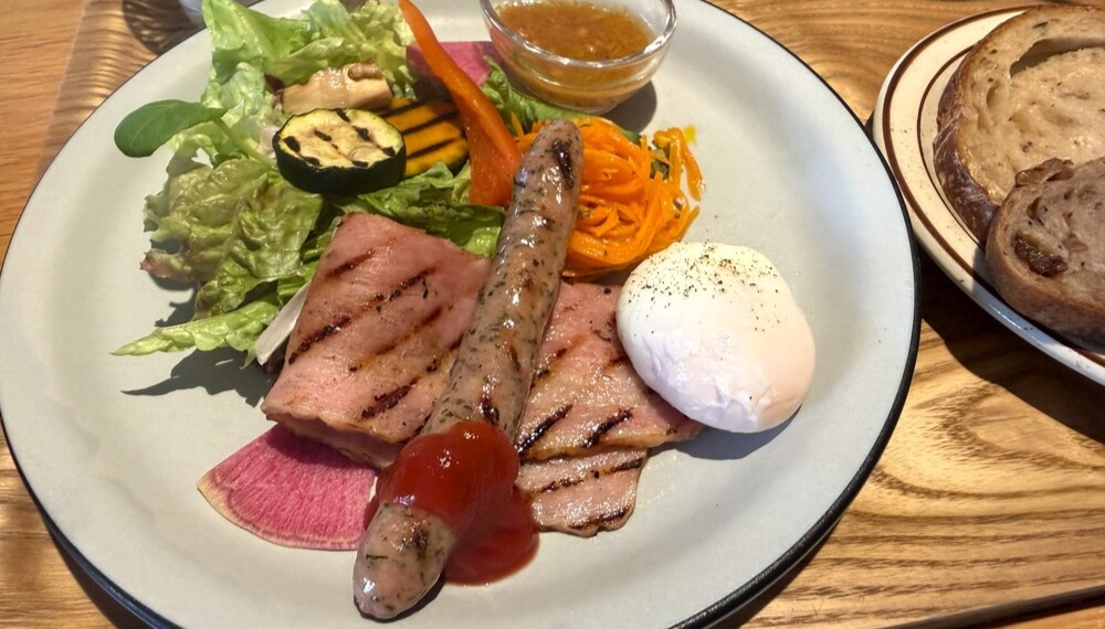 焼き目の付いたソーセージやベーコンと野菜を盛り付けたプレート